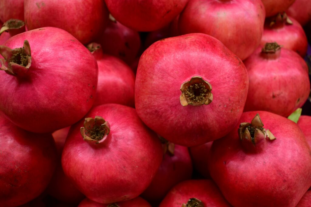 A vibrant close-up image of fresh ripe pomegranates displaying their natural red hue.
