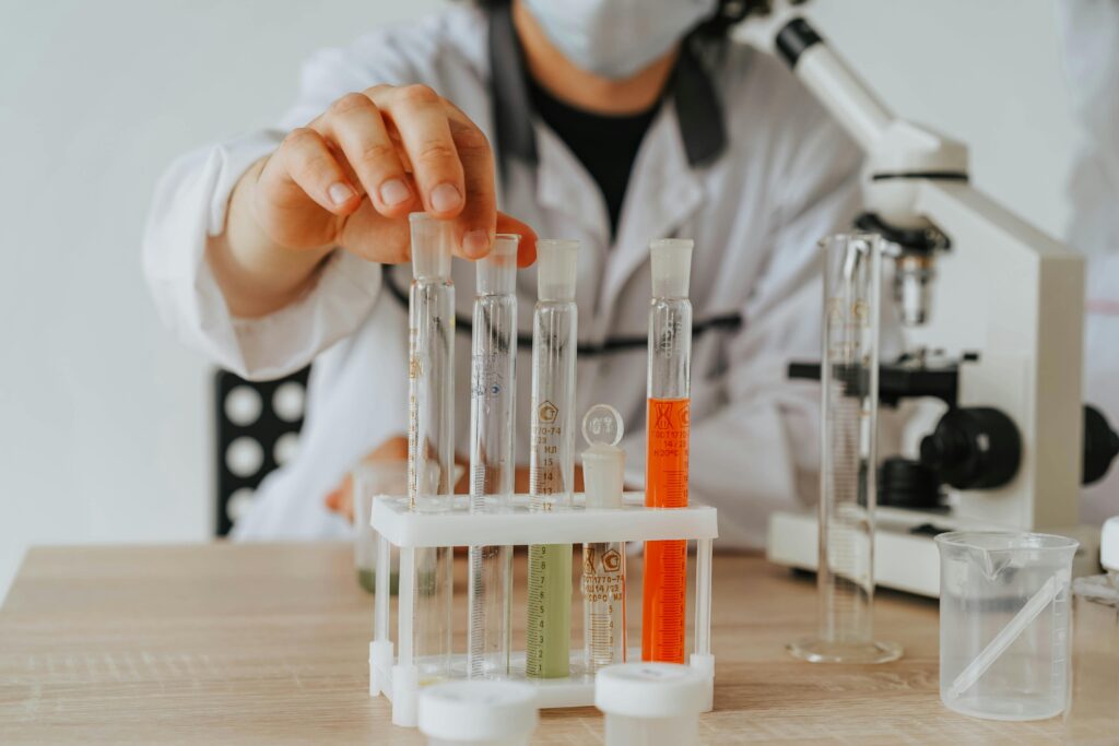 Scientist in lab coat conducting an experiment with test tubes and a microscope.